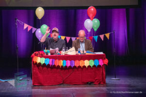 Ralf Kramp und Sebastian Carsten Henn auf der Bühne des Buchmesse Saar Festivals 2026, LIVE im Theater am Ring in Saarlouis