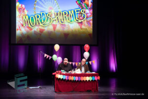 Ralf Kramp und Sebastian Carsten Henn auf der Bühne des Buchmesse Saar Festivals 2026, LIVE im Theater am Ring in Saarlouis